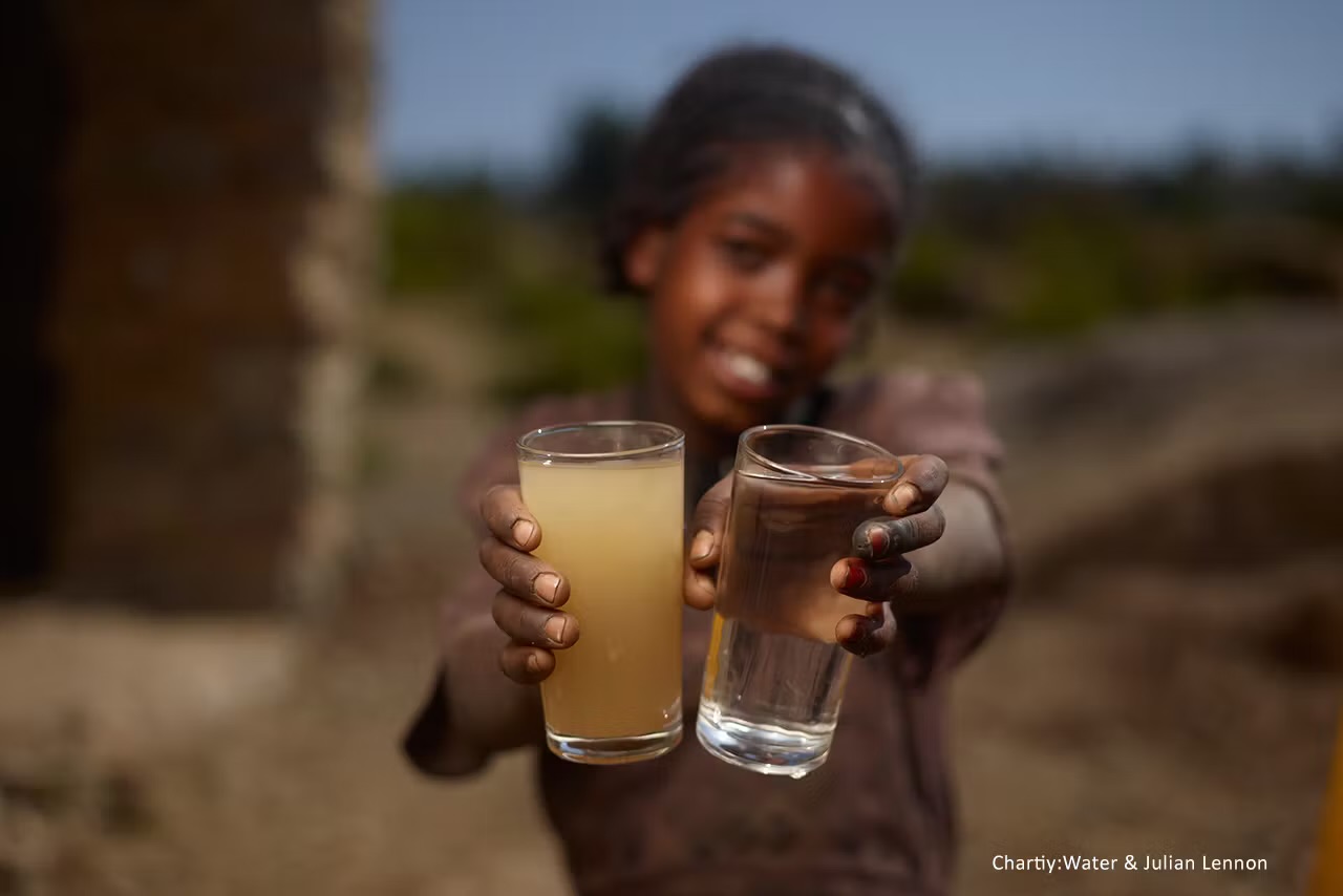 A child holding glasses of clean water, representing access to clean water in rural African communities
