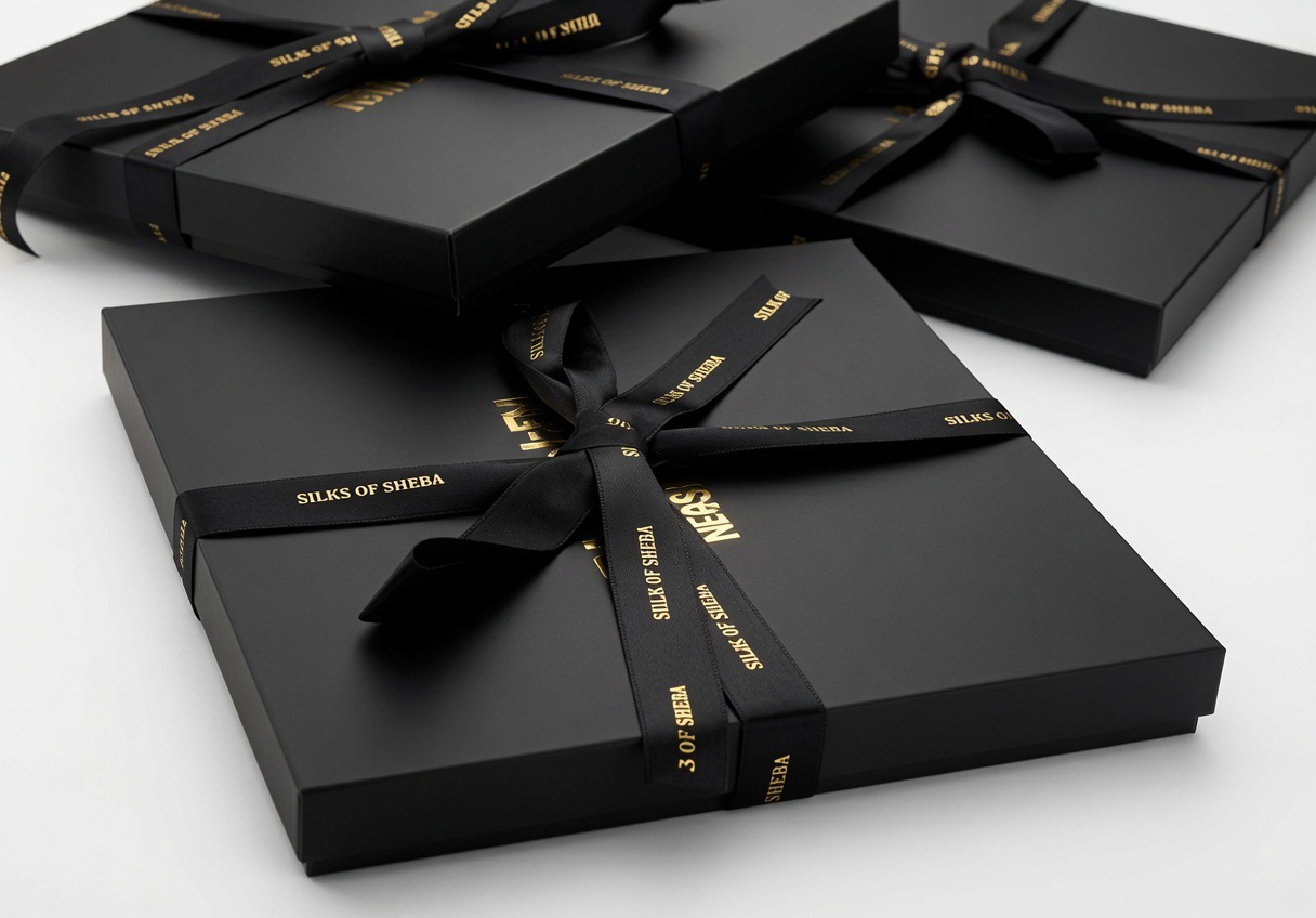 Close-up of Silks of Sheba ribbon-tied boxes with gold foil branding